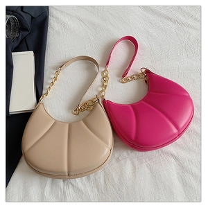 Detail of shell-textured underarm bags in beige and pink with chain straps and gold zippers