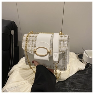 Detailed shot of white tweed texture and golden oval metal lock on a crossbody bag