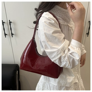 Detailed shot of dark red glossy patent leather hobo bag with sleek metallic zipper