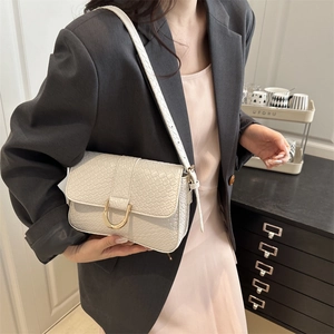 Cream textured flap shoulder bag with gold horseshoe buckle worn by model