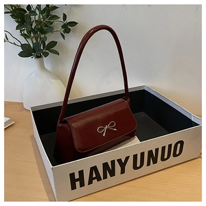 Détail du sac à main en cuir verni bordeaux avec un nœud métallique argenté élégant