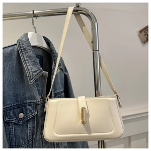 Detailed view of cream baguette bag with gold buckle fastener on a hanger display
