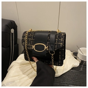 Close-up of black tweed plaid shoulder bag with golden oval buckle and chain strap