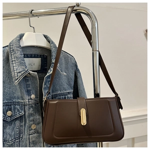 Detail of dark brown leather shoulder bag with a sleek gold rectangular metal buckle