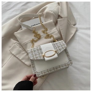Detail of elegant beige tweed and white leather crossbody bag with golden chain strap