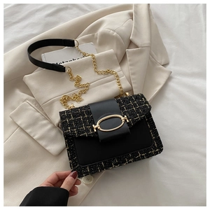 Close-up of black tweed and leather shoulder bag with elegant gold metal buckle