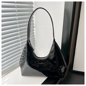 Detail of high-gloss black patent leather hobo bag featuring silver logo and top zipper