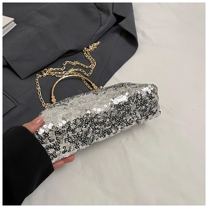 Detail of silver sequin shell bag with gold metal handle and chain strap for women