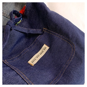 Detail of denim bag showing orange stitching, ethnic pattern lining and fabric label