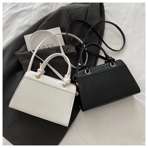 Close-up of minimalist black and white crossbody bags with gold rings and knot handles