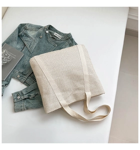 Détail du sac cabas beige tissé avec texture en maille et larges anses en ruban