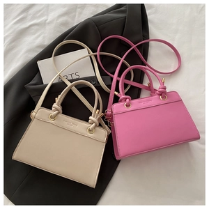 Close-up of minimalist trapezoid handbags in beige and pink with gold hardware detail