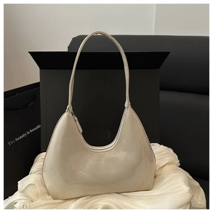 Detail of glossy beige patent leather hobo bag with a sleek metallic zipper closure