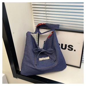 Detailed view of dark blue denim hobo bag featuring a bow pocket and contrast floral lining