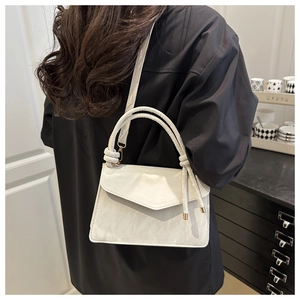 Model wearing a cream-colored marble texture leather handbag with a top handle and strap