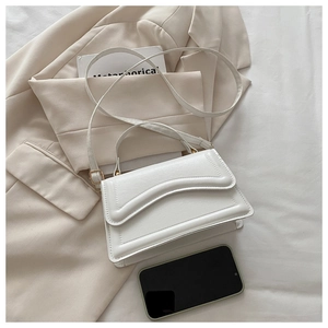 Sac blanc chic avec coutures ondulées stylisé avec un blazer beige et des livres