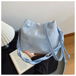 Détail du sac seau bleu clair avec texture plissée et bandoulière réglable