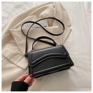 Détail du sac à main en cuir noir avec matelassage incurvé et bandoulière réglable