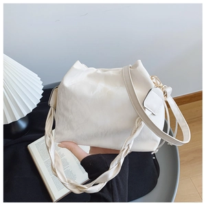 Gros plan du sac seau plissé blanc avec poignée tressée et détails en métal doré