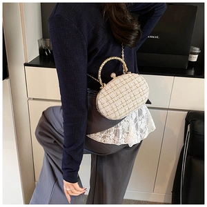 Dettaglio della borsa in tweed beige con manico in metallo dorato sulla spalla
