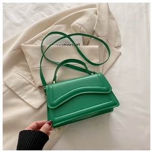 Détail d'un sac en cuir vert avec surpiqûres ondulées horizontales et fermoir doré chic