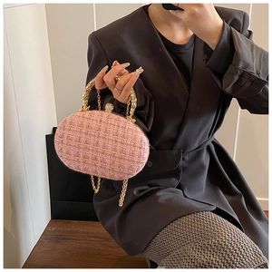 Pink tweed woven evening bag with golden chain and metallic handle carried by a model
