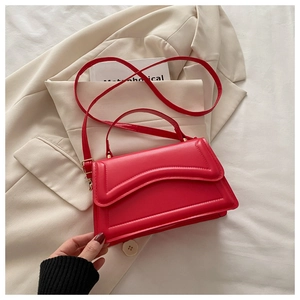 Vue détaillée du sac en cuir rouge avec coutures ondulées sur un blazer beige