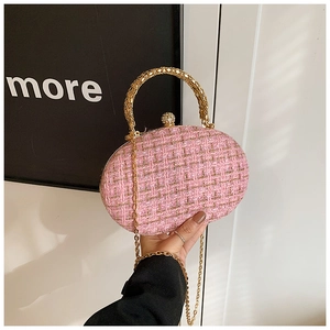 Detail of pink tweed texture and ornate gold metal handle on elegant crossbody bag