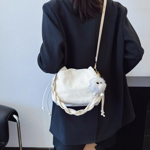 Sac seau texturé crème minimaliste avec charme en peluche sur un blazer noir