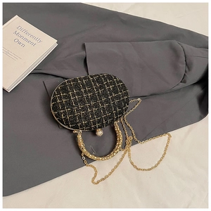 Close-up of black and gold tweed evening clutch with chain strap and rhinestone clasp