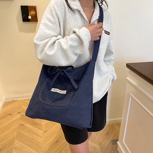 Deep blue denim reversible tote bag with decorative drawstring and white letter patch