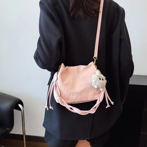 Sac seau rose plissé avec charme en peluche sur un modèle en blazer noir