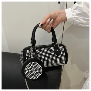 Macro detail of rhinestone cylinder bag with metallic chain and matching mini pouch