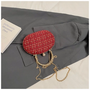 Detail view of red tweed evening clutch with gold chain and rhinestone spherical lock