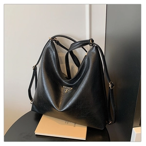 Detail of black lychee-textured PU leather hobo bag with triangle metal logo and straps