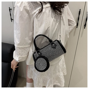 Macro detail of black cylindrical crossbody bag with silver studs and small round purse