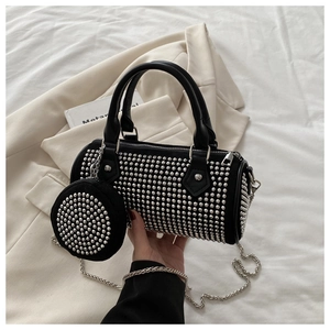 Close-up of black cylinder bag with silver studs and a chain shoulder strap