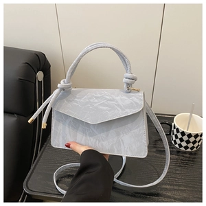 Detailed view of the wrinkled texture PU leather and knotted handle on a grey handbag