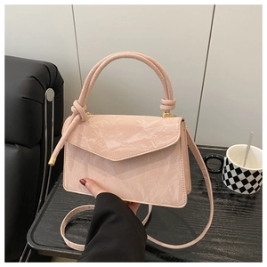 Detail of light pink pleated handbag with V-flap and elegant decorative handle knot
