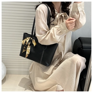 Detail of black tote bag with white contrast stitching and elegant silk scarf handle decoration