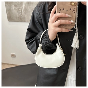 Dettaglio di una borsa a mezzaluna bianca con trama in pelle liscia e anelli in metallo dorato