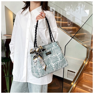 Detail of green and white striped tote bag with silk scarf on model in white shirt