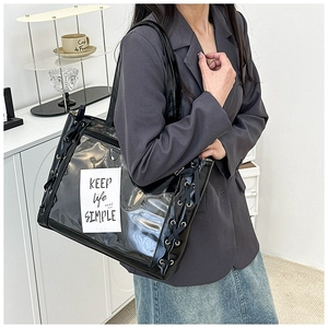 Detail of ribbon lacing on a black PVC tote bag with clear panel and shoulder strap