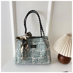 Close-up of green striped woven tote bag with silk scarf and fashion leather tag