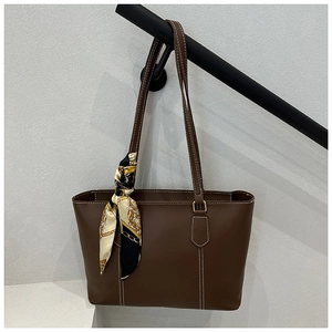 Close-up of brown leather tote bag featuring white contrast stitching and silk scarf