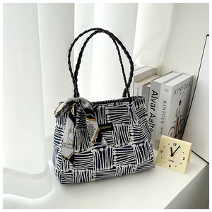 Detail of striped canvas tote bag with woven leather handle and decorative silk scarf