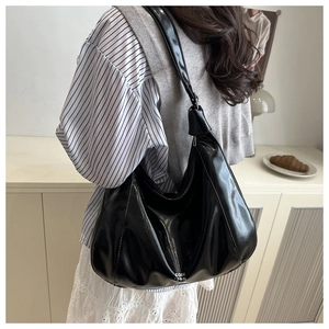 Vista posteriore di una persona con borsa hobo nera lucida con logo sulla parte bassa