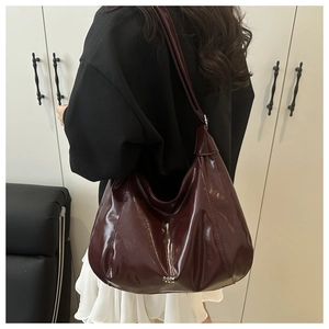 Dettaglio della grande borsa tote bordeaux in pelle verniciata lucida con tracolla regolabile