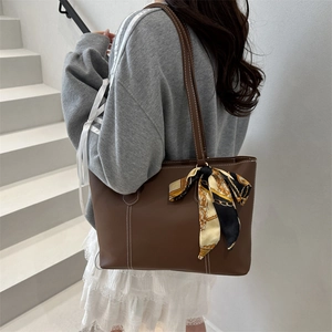 Minimalist dark brown leather tote bag with a silk scarf and white contrast stitching detail