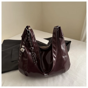 Dettaglio borsa hobo in vernice bordeaux con campanello d'argento e ciondolo in corda intrecciata